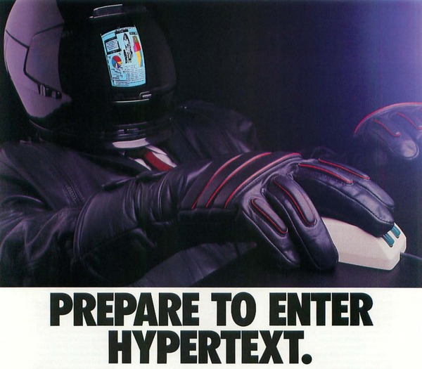 An old advertisement showing someone in a car racing suit and helmet sitting at a computer. It reads: prepare to enter hypertext.